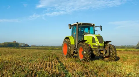 A green tractor with large red wheels parked in a field