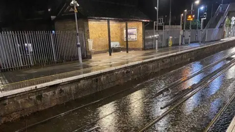 Network Rail A flooded railway line seen with a platform in the background