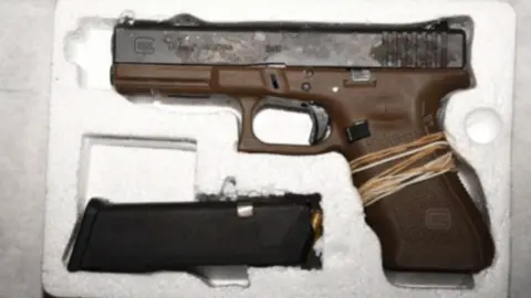 Merseyside Police A semi-automatic handgun in a polystyrene case with a brown handle and elastic bands wrapped around the grip, and a black ammunition clip with a bullet visible at the top