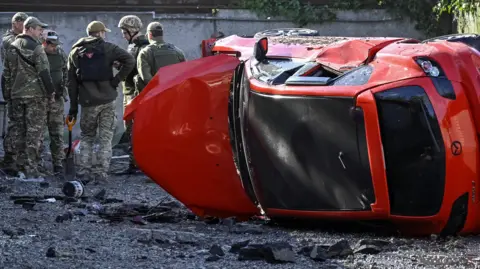 Ukrainian forces inspect a damaged car