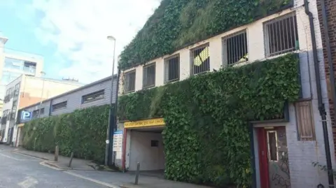 A multi-storey car park with green foliage planted vertically on the wall facing the street