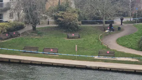 Liz Saul/BBC An grassy area next to the River Thames at Chertsey cordoned off with police tape