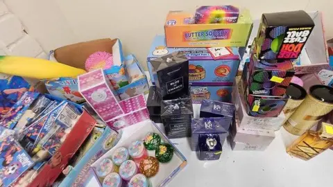 Gloucestershire County Council Many boxes of toys are pictured stacked on a white table. Most are small boxed toys.