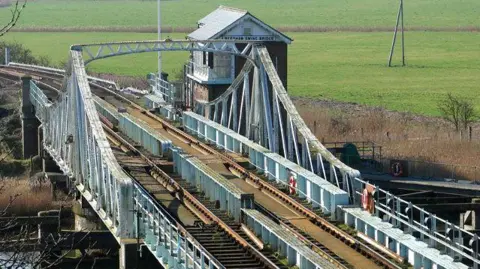 Evelyn Simak/Geograph A railway swing bridge from above, with the railway tracks in view above the river.