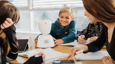 No Inclusion A pupil holds a robot while it is on a desk in a classroom