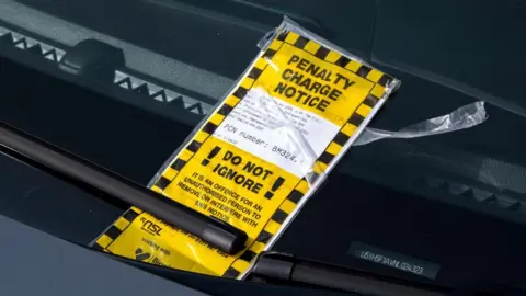 Mike Kemp/In Pictures via Getty Images A penalty charge notice fixed beneath a windscreen wiper on a car