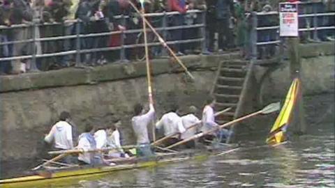 Cambridge crew in broken boat making their way back on to land as spectators watch on