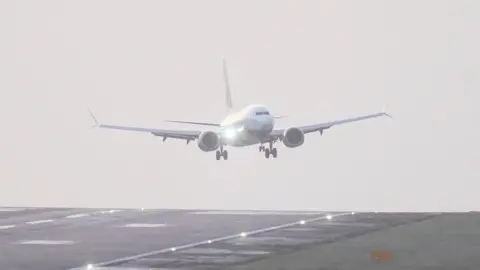 A white plane landing on the runaway at Leeds Bradford Airport