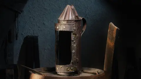 Ashmolean Brown and black lantern with rusted bolts. 