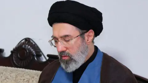 West Asia News Agency Via Reuters Wearing a black turban and spectacles, Mojtaba Khamenei is pictured during a visit to Hezbollah's office in Tehran in 2024. 