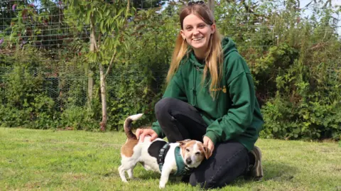 A woman kneeling down next to a dog