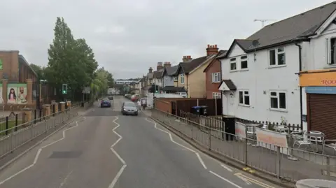Google Maps Maybury Hill in Woking with railings around the edge and traffic lights with a pedestrian crossing
