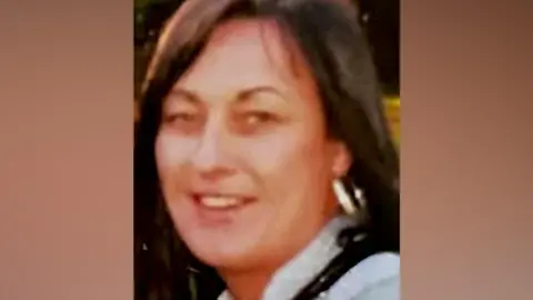 Handout A woman with long brown hair, a hoop earring and a blue top smiles for the camera.