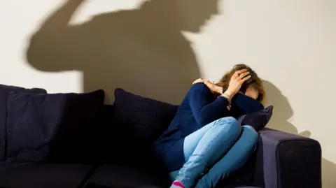 Dominic Lipinski/PA Wire A shadow of a man with a clenched fist as a woman cowers in the corner