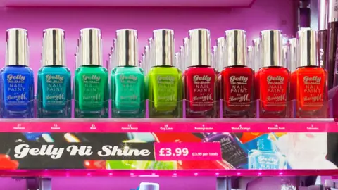 A row of very brightly coloured Barry M nail varnish bottles in a close up shot of a shop display