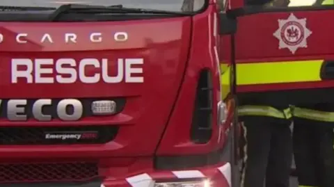 A red fire engine is seen from the front with the door open. 