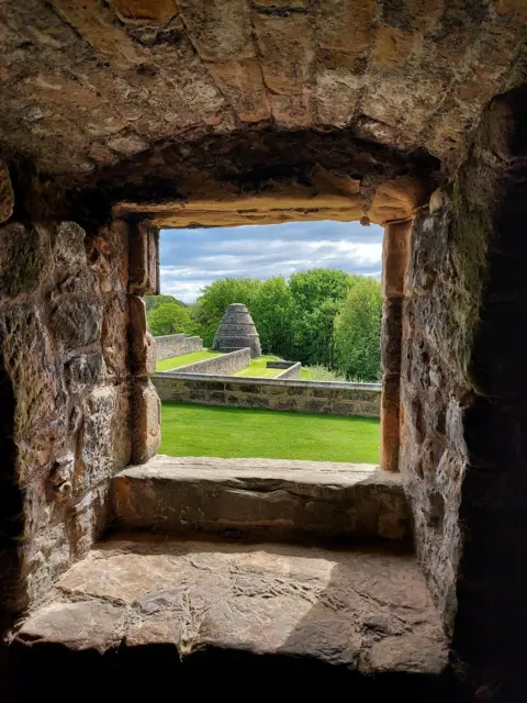 Krystal Hanley A stone alcove overlooking a garden 