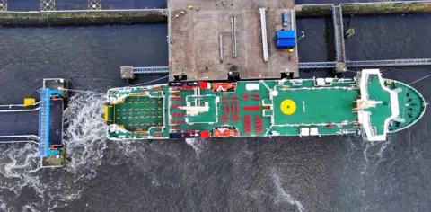 Tom Lennon Aerial view of a large ship with green decks and red outdoor seats