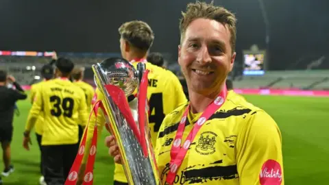 Gloucestershire spinner Tom Smith holds the T20 Blast trophy after his side's win in 2024