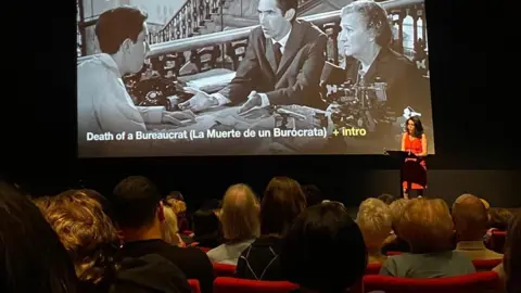 Founder Ketty Rodriguez introducing a screening of Cuban film, Death of a Bureaucrat in a cinema
