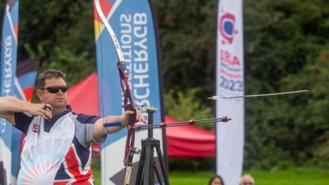 Clive Jones in team GB clothing, shooting an arrow