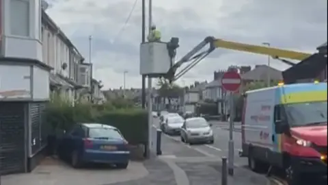 Mark Butcher A worker uses a crane to remove a union jack on a street in Blackpool