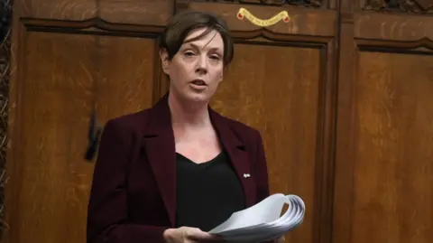 Reuters Jess Phillips speaking in the Commons. She wears a dark purple jacket and a black top