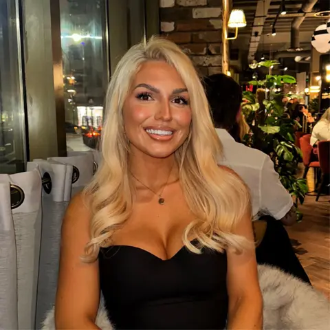 Sharna Beveridge Woman with blonde hair wearing a black dress smiling 