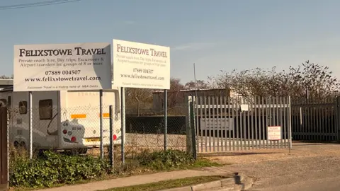 Richard Daniel/BBC The outside of the yard where Felixstowe Travel operated. There are two branded signs on the other side of the fence.