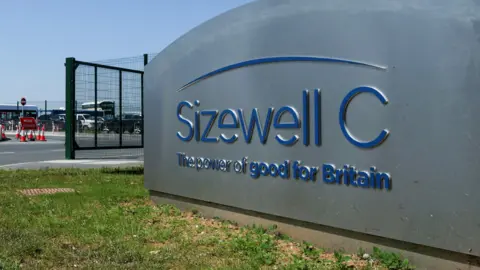 An entrance sign at the Sizewell C construction site. It is a grey sign with blue writing that reads: "Sizewell C, The power of good for Britain".