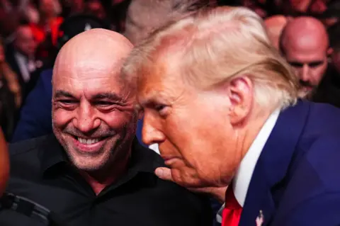 Getty Images A close up of Joe Rogan smiling, with Trump in profile, his hand on Rogan's shoulder