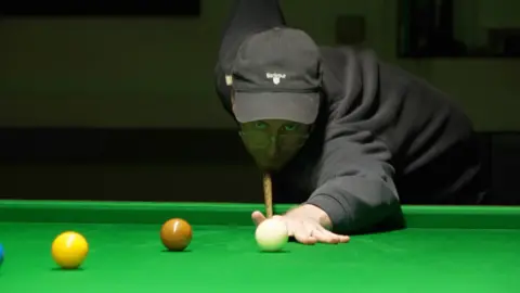 A man is playing snooker. 