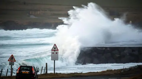 Getty Images Large waves are seen colliding with land in a quiet coastal town the Shetland 