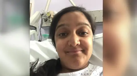 Sanju Pal Sanju Pal, with her black hair tied in a ponytail smiles, into the camera from her hospital bed