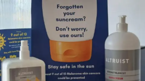LDRS Bottles of sun cream displayed beside a Sun Safe Sheffield information sign encouraging people to stay safe in the sun and use free sun cream.