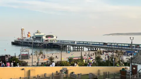 View from the road looking down at Bournemouth Pier and beach below in the aftermath of the disorder. A few people remain on the beach.
