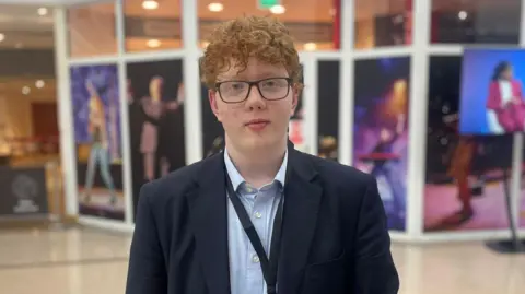 Henry Churchill, a 17-year-old young red-haired man wears a suit with a blue shirt at the Conservative Party conference 