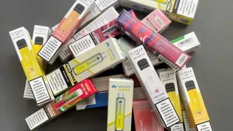 An assortment of disposable, multi-coloured vapes.
