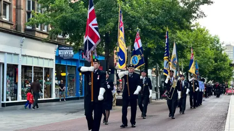 Military standard bearers march down Leicester High Street