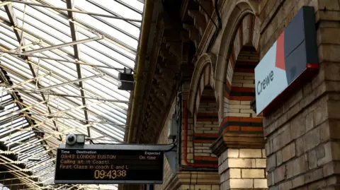 Reuters An information board and a sign that says Crewe at Crewe Station in Cheshire