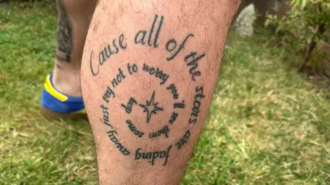 Stuart McCullagh A tattoo of Oasis lyrics in a concentric circle with a star at the centre, reading "cause all of the stars are fading away just try not to worry you'll see them some day".