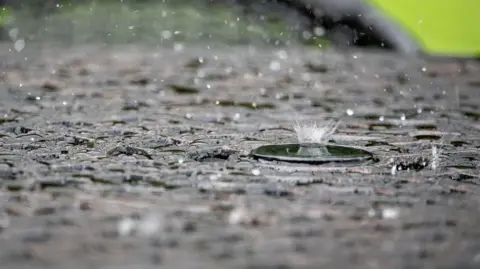 Raindrops splashing on the pavement up close. 