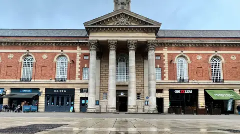 BBC Peterborough City Council's entrance is in the middle. The building is made up of red bricks, and has pillars outside.