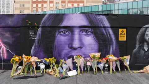 Fans gather at Black Sabbath landmarks as Birmingham mourns death of Ozzy Osbourne 1 PA Media Floral tributes are left by the Sabbath mural, which is black and purple. Ozzy's likeness can be seen, with bunches of flowers lined up on the floor beneath it.