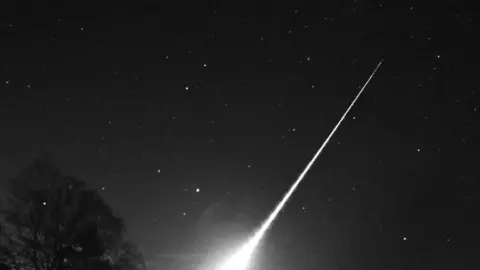 A white streak can be seen across the night's sky. Pictured from below.
