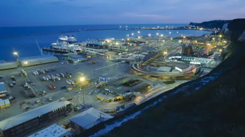 Getty Images A view of the port of Dover at dusk from the White Cliffs above the port, showing ferries and traffic.