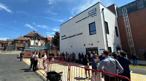 Image shows the Hinckley Community Diagnostic Centre with people standing outside. 