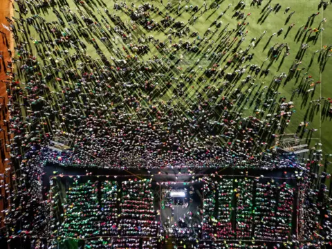 ZOHRA BENSEMRA / REUTERS 
A drone view shows people near a stage in a large field. 