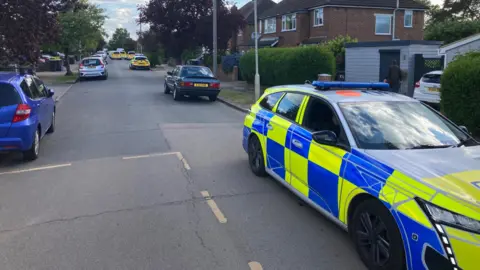 A police car outside a property in Bedford - there are other cars on the street in the distance.