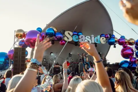 Victorious Festival Seaside sign and stage at Victorious Festival with crowd in front.